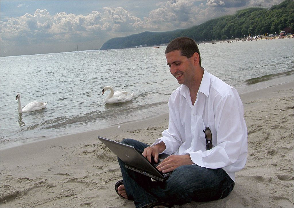 Paweł Krzyworączka z laptopem na plaży